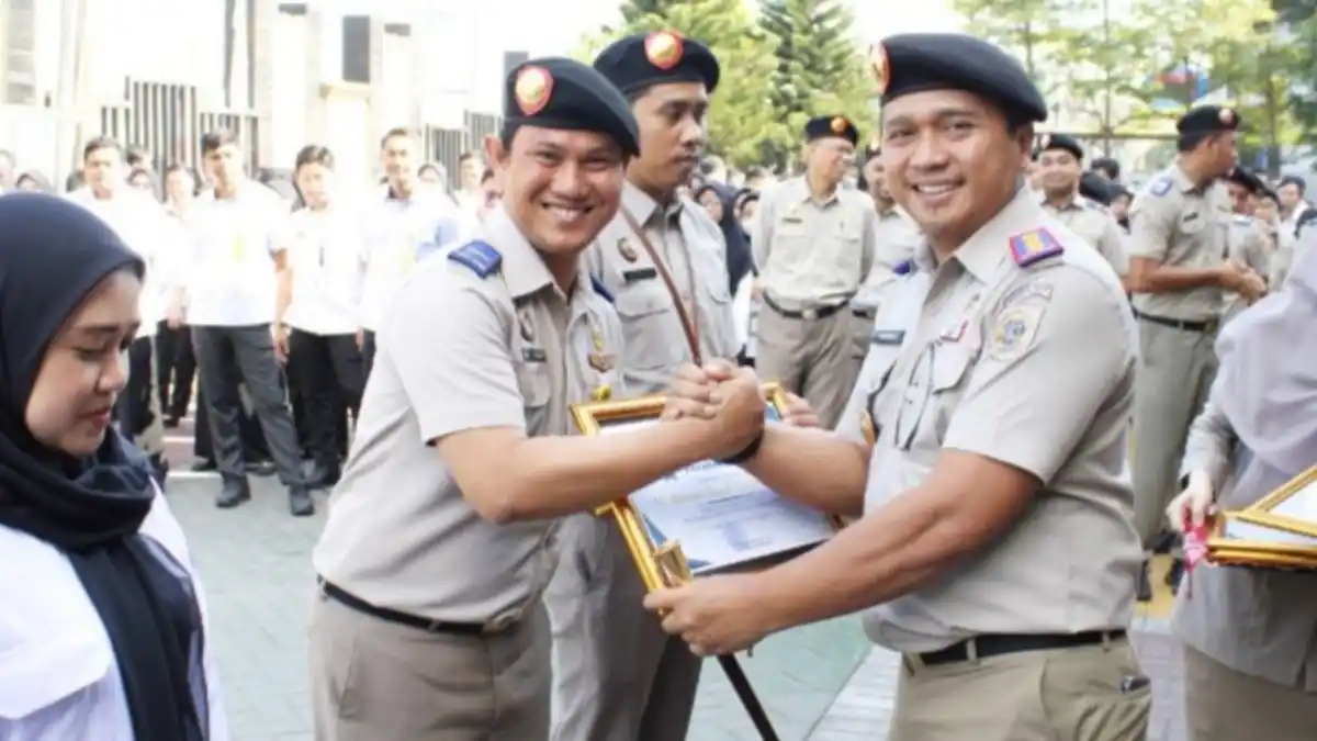 Petugas Kantor Pertanahan Kota Makassar menyerahkan piagam apresiasi kepada pegawai berprestasi usai upacara peringatan 65 Tahun UUPA di halaman kantor, Rabu 24/09/2025