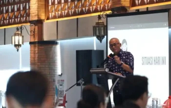 Ndoro Kakung berdiri di podium memberikan materi kehumasan digital pada kegiatan Diskominfo Makassar di sebuah hotel kota