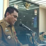 Pejabat Pemerintah Kota Makassar menyampaikan sambutan di podium saat sosialisasi Perwali 23 Tahun 2021 tentang pengelolaan hibah dan bantuan sosial