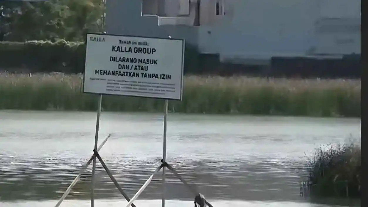 Sengketa Tanah 16,4 Hektare Tanjung Bunga, Klaim Baru Muncul dari Pengusaha Mulyono Tanuwijaya 1 Papan peringatan bertuliskan larangan masuk di atas lahan sengketa 16 4 hektare kawasan Tanjung Bunga Makassar dengan latar permukiman dan kanal air pada 5 November 2025