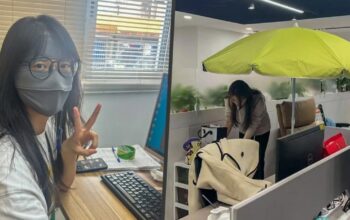 Tren Pekerja China Pakai Payung di Meja Kantor Lawan Paparan Cahaya dan Udara Kering